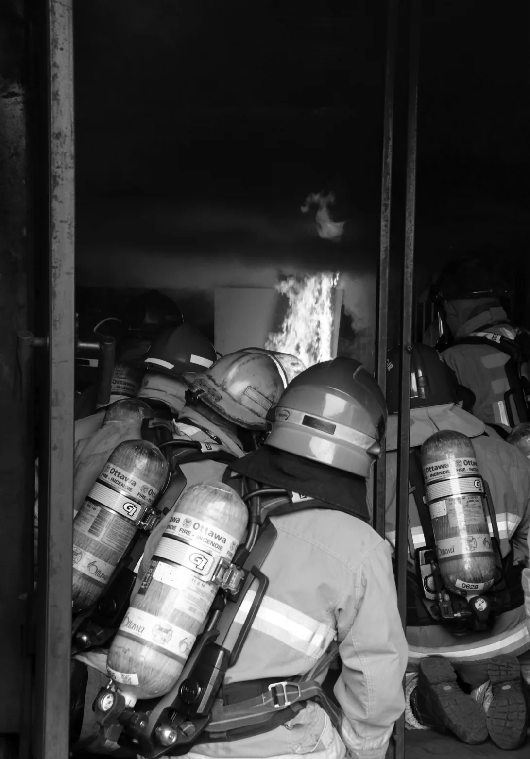 Ottawa Fire Services firefighters in close quarters with flames visible behind them during a live fire training evolution