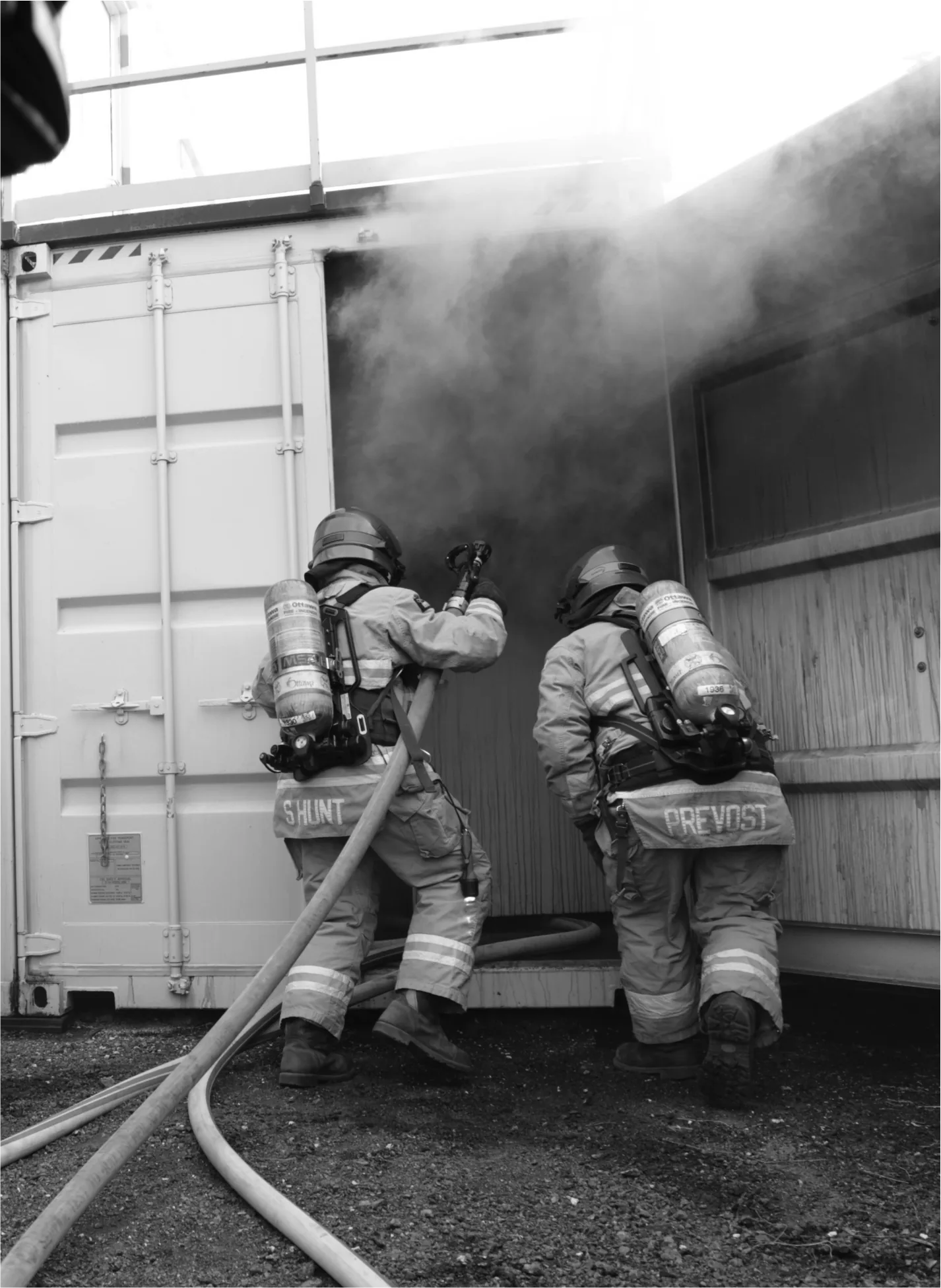 Two Ottawa Fire Services firefighters with SCBA entering a smoke-filled training container
